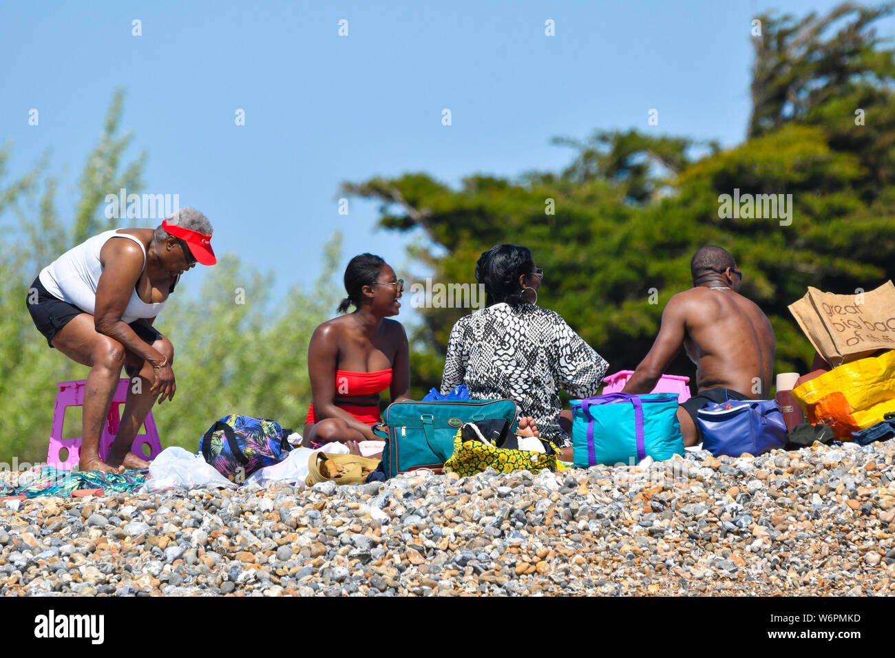 Une famille noire ensemble sur une plage sur une chaude journée de printemps dans le West Sussex, Angleterre, Royaume-Uni. Banque D'Images