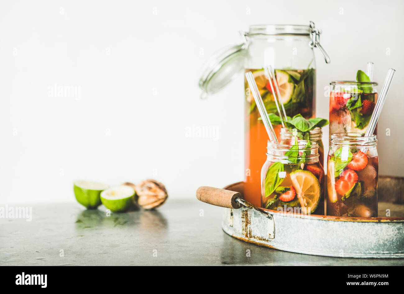 Fraise et basilic fait maison ou Limonade Thé glacé dans le verre sans poignée avec eco-friendly pailles plastique sur le plateau métallique rustique, mur blanc à backgrou Banque D'Images