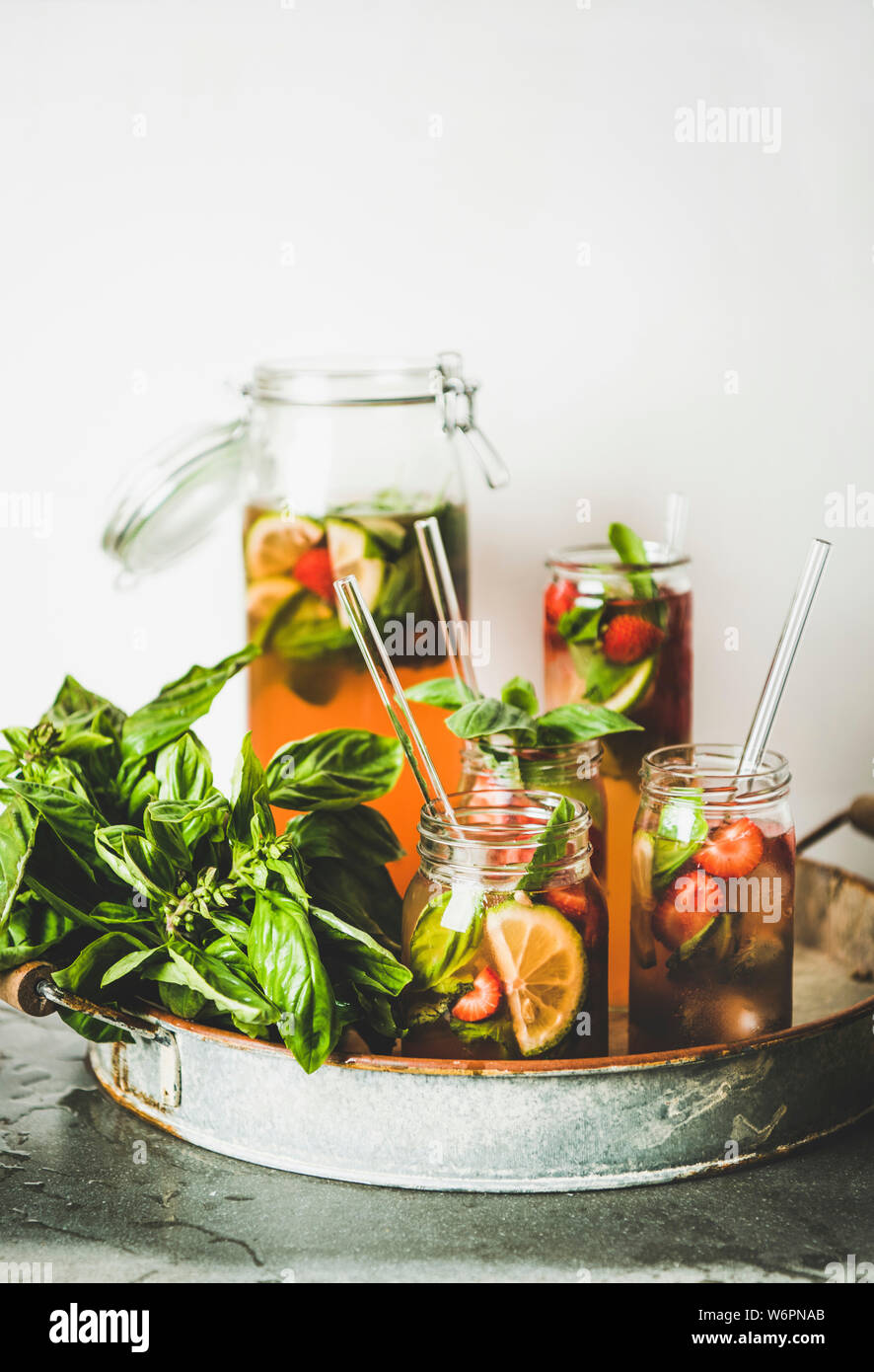 Fraises fraîches faites maison et basilic ou Limonade Thé glacé-verre en verres avec eco-friendly verre plastique pailles-sur le plateau métallique, blanc rustique wal Banque D'Images
