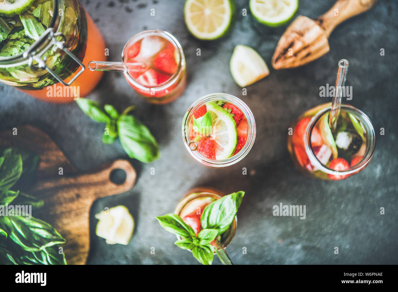 Des fraises fraîches de basilic et glace limonade ou plateau en verre double paroi avec eco-friendly pailles plastique gris foncé sur fond de table top, v Banque D'Images