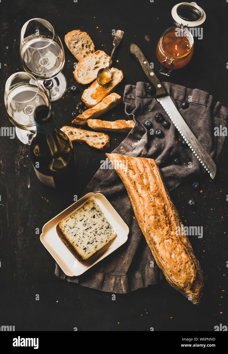 Vin et snack-set. Télévision à jeter des tranches de pain, fromage, confiture d'abricot, de petits fruits et vin blanc sur fond noir rustique, vue du dessus Banque D'Images
