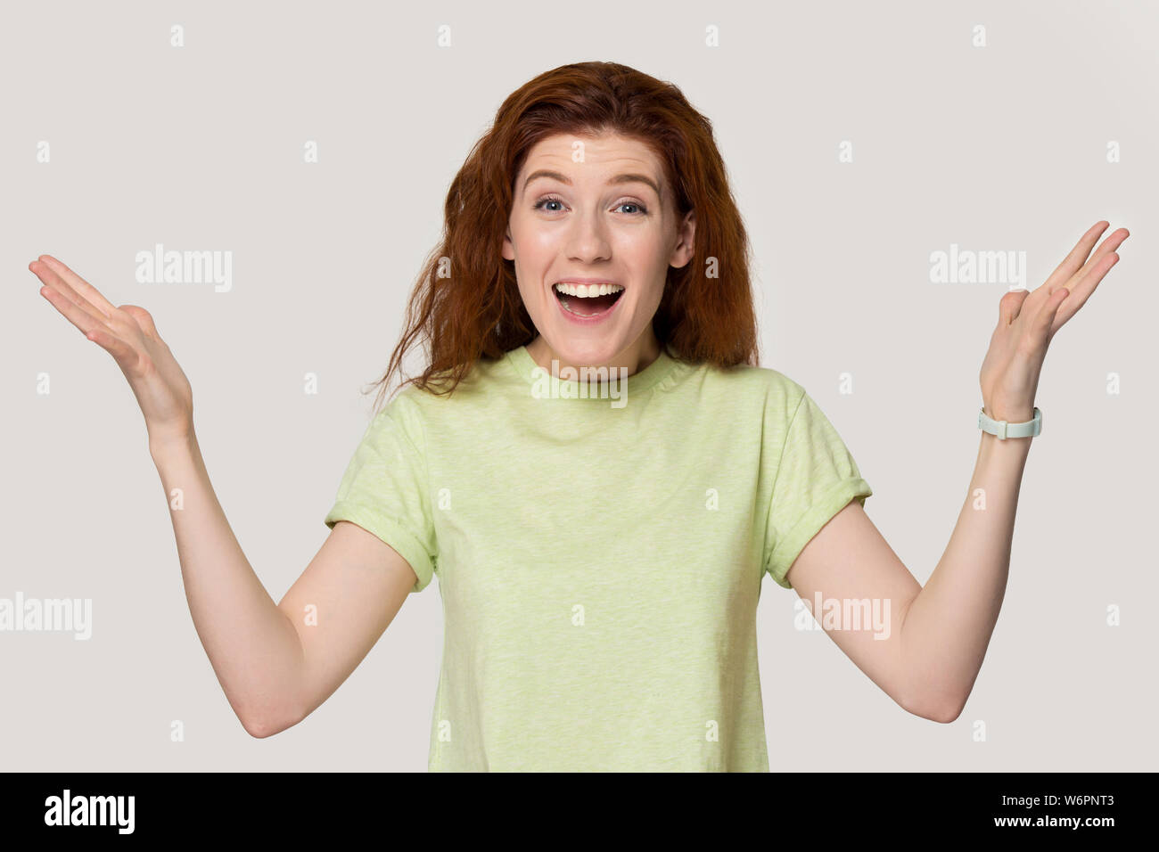 Femme rousse heureux excité soulever palms posant sur fond gris Banque D'Images