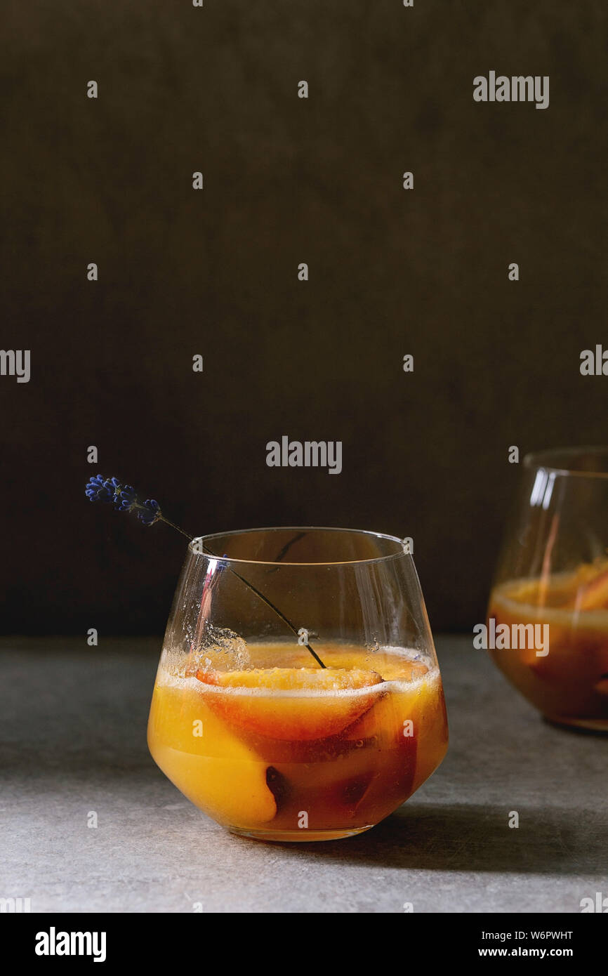 Peach Bellini cocktail froid limonade ou avec des fleurs de lavande servi dans deux verres sur la texture sombre tableau. Boisson d'été à la maison. Copy space Banque D'Images
