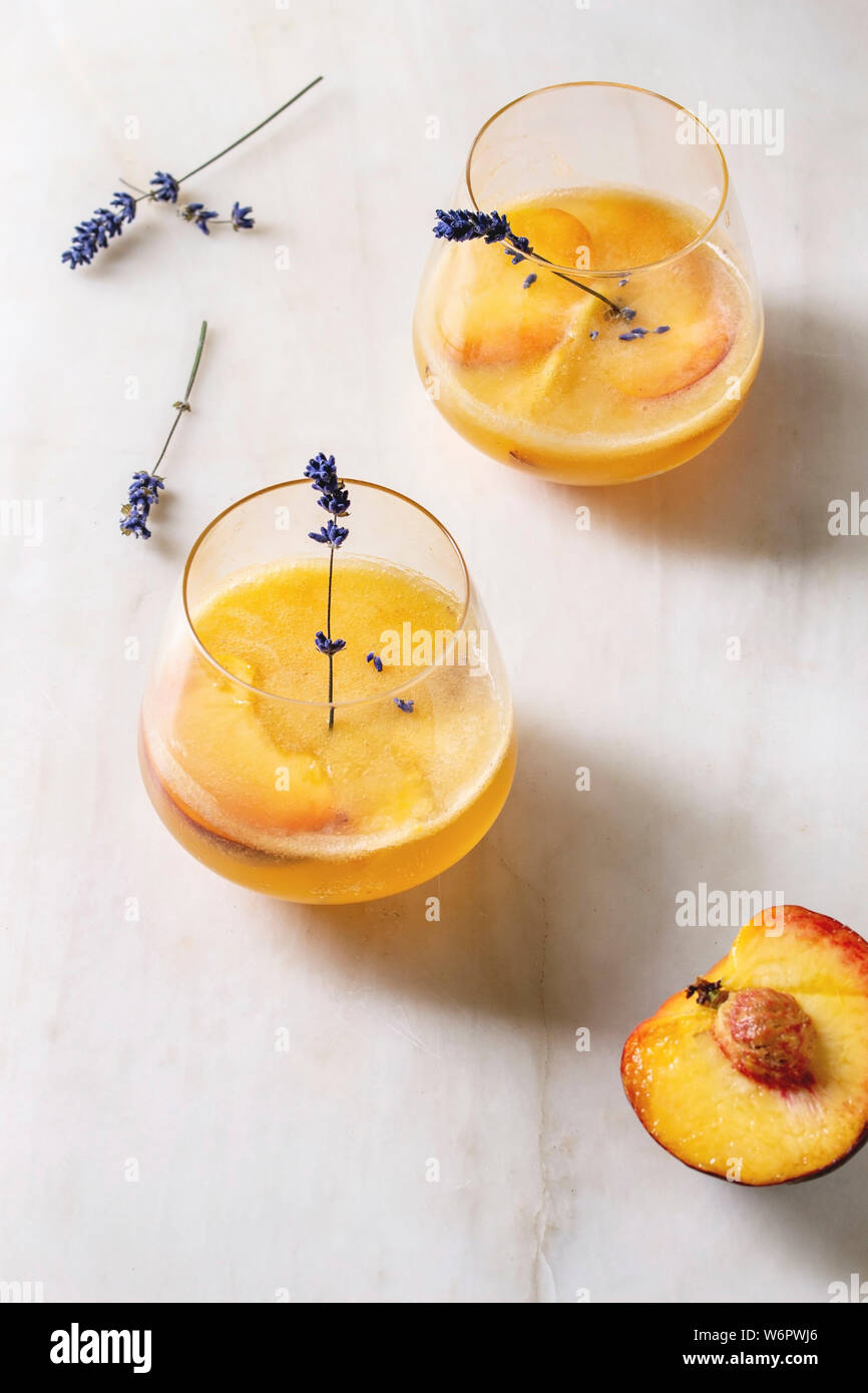 Peach Bellini cocktail froid limonade ou avec des fleurs de lavande servi dans deux verres sur la table de marbre blanc. Boisson d'été à la maison. Banque D'Images