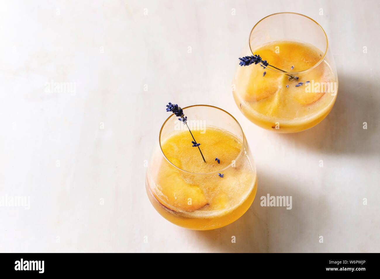 Peach Bellini cocktail froid limonade ou avec des fleurs de lavande servi dans deux verres sur la table de marbre blanc. Boisson d'été à la maison. Copy space Banque D'Images