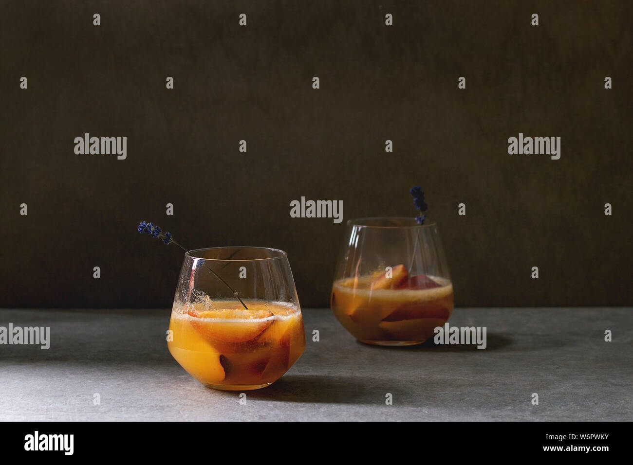 Peach Bellini cocktail froid limonade ou avec des fleurs de lavande servi dans deux verres sur la texture sombre tableau. Boisson d'été à la maison. Copy space Banque D'Images
