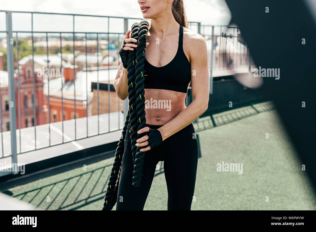 Méconnaissable femme avec une corde sur l'épaule de combat debout sur une terrasse. Jeune athlète prenant une pause. Banque D'Images