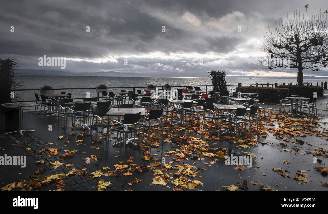 En plein air de l'automne paysage avec tables et chaises vides humides, sur la terrasse d'un restaurant sur les rives du lac de Constance, à Friedrichshafen, Allemagne. Banque D'Images
