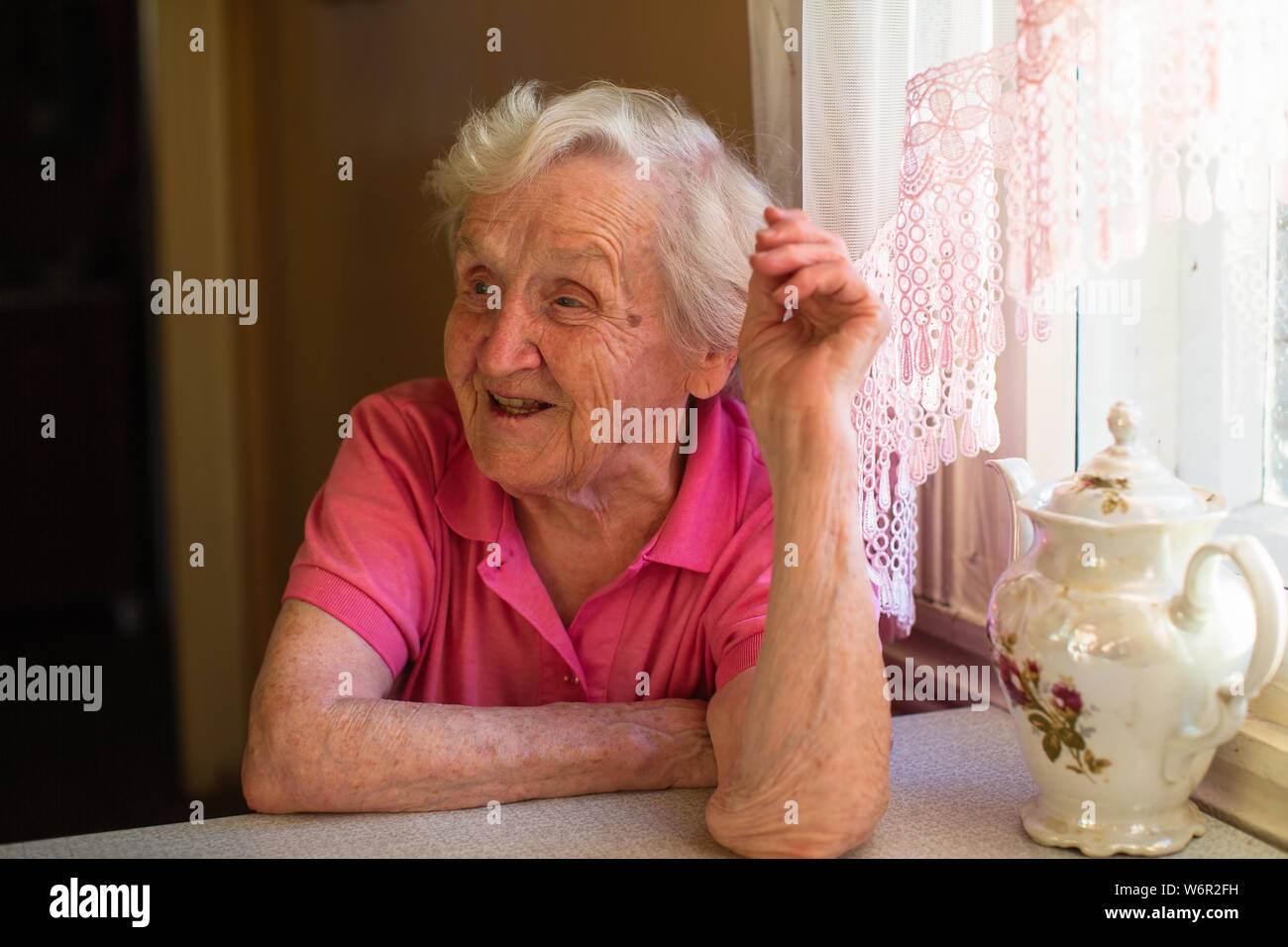 Portrait de femme cheerfulelderly assis à la table. Banque D'Images