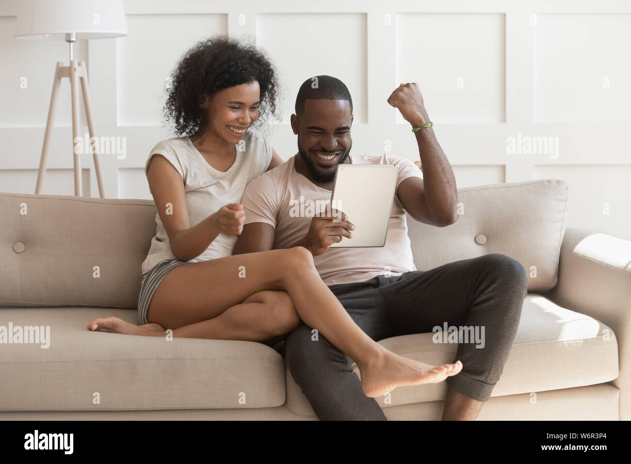 Heureux happy african couple looking at digital tablet se sentir gagnants Banque D'Images