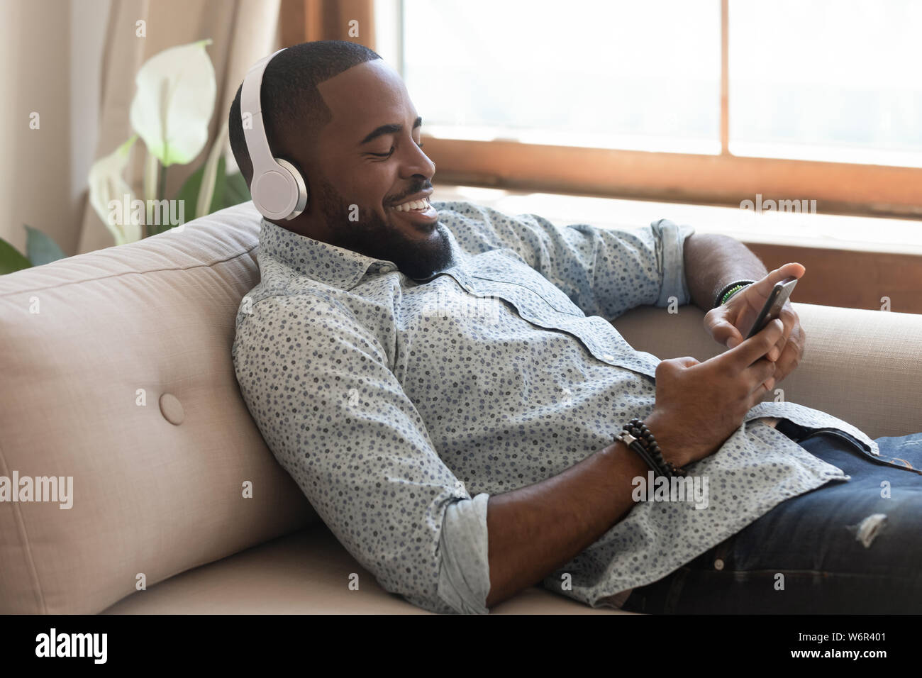 Ambiance african man wearing headphones listening music mobile sur smartphone Banque D'Images