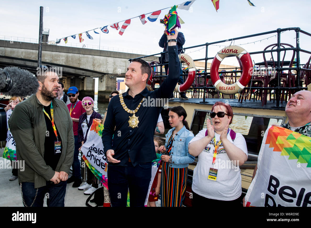Maire de Belfast John Finucane vagues du drapeau arc-en-ciel qui lui a été présenté par la fierté des militants, à la suite d'une flottille de bateaux portant des drapeaux arc-en-ciel en avant de la Belfast Pride Parade le samedi. Banque D'Images
