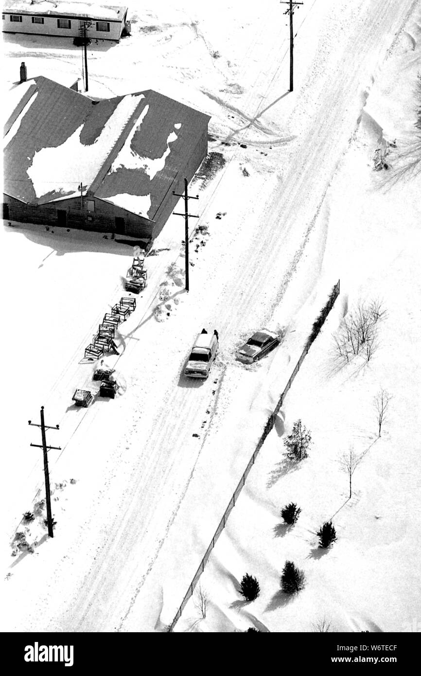 Jour de neige et les voitures doivent être séparés des amoncellements de neige sur une route de campagne. Banque D'Images