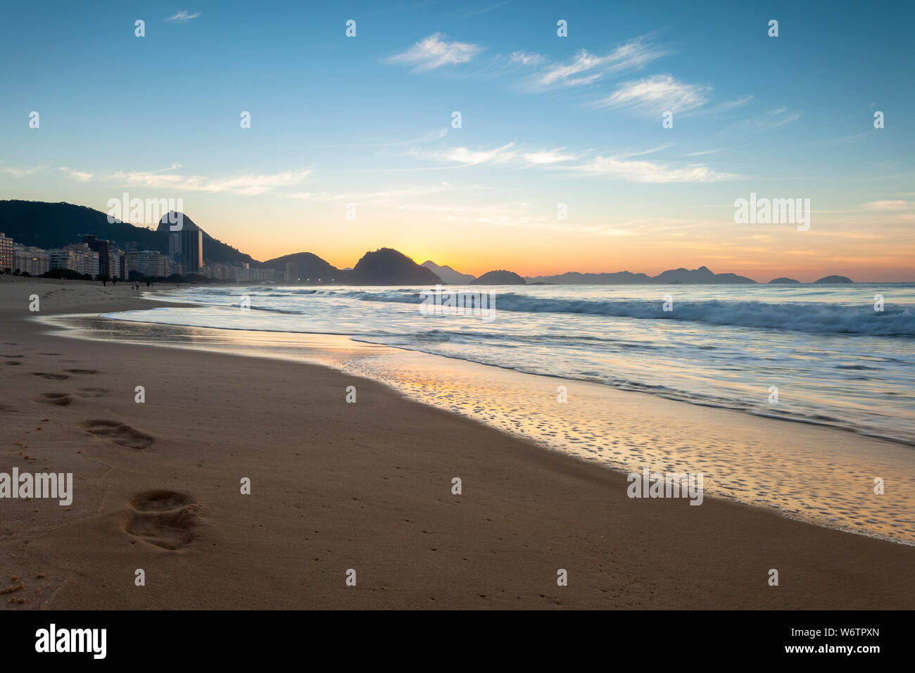 Tôt le matin, la plage de Copacabana à Rio de Janeiro avec le Mont Sugarloaf en arrière-plan juste avant le lever du soleil avec des couleurs orange et bleu Banque D'Images