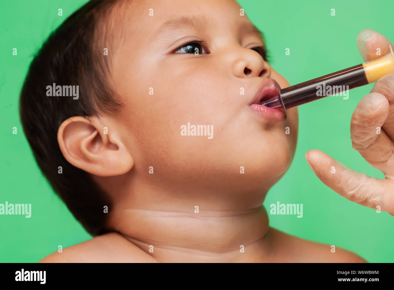Un mignon petit garçon prenant la posologie appropriée de la médecine grippe seringue orale par le biais d'un professionnel de la santé. Banque D'Images