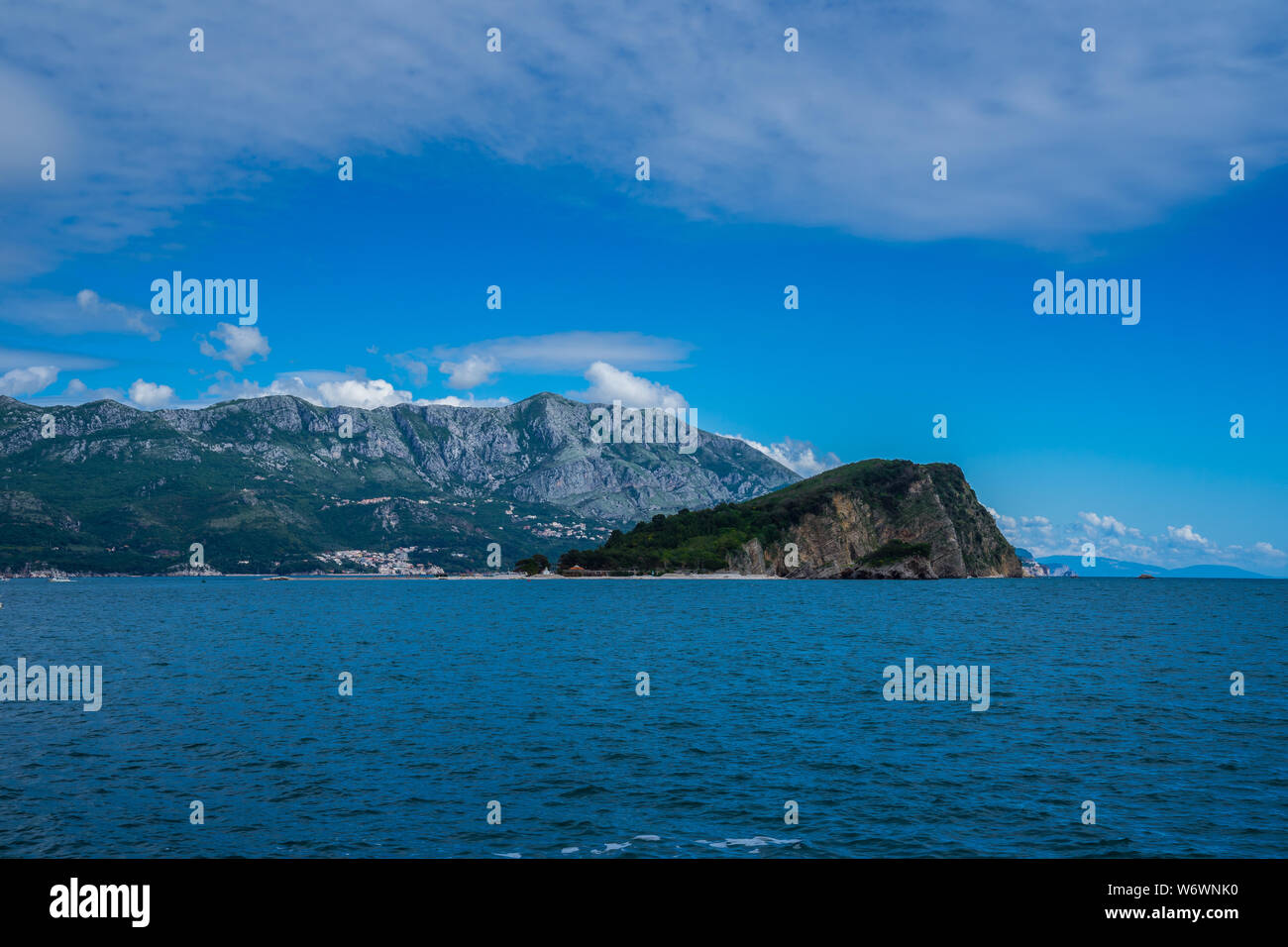 Le Monténégro, beau petit îlot vert sveti nikola avec célèbre Hawaï plage sable à côté de la côte de Budva ville entouré par de majestueuses montagnes noires Banque D'Images