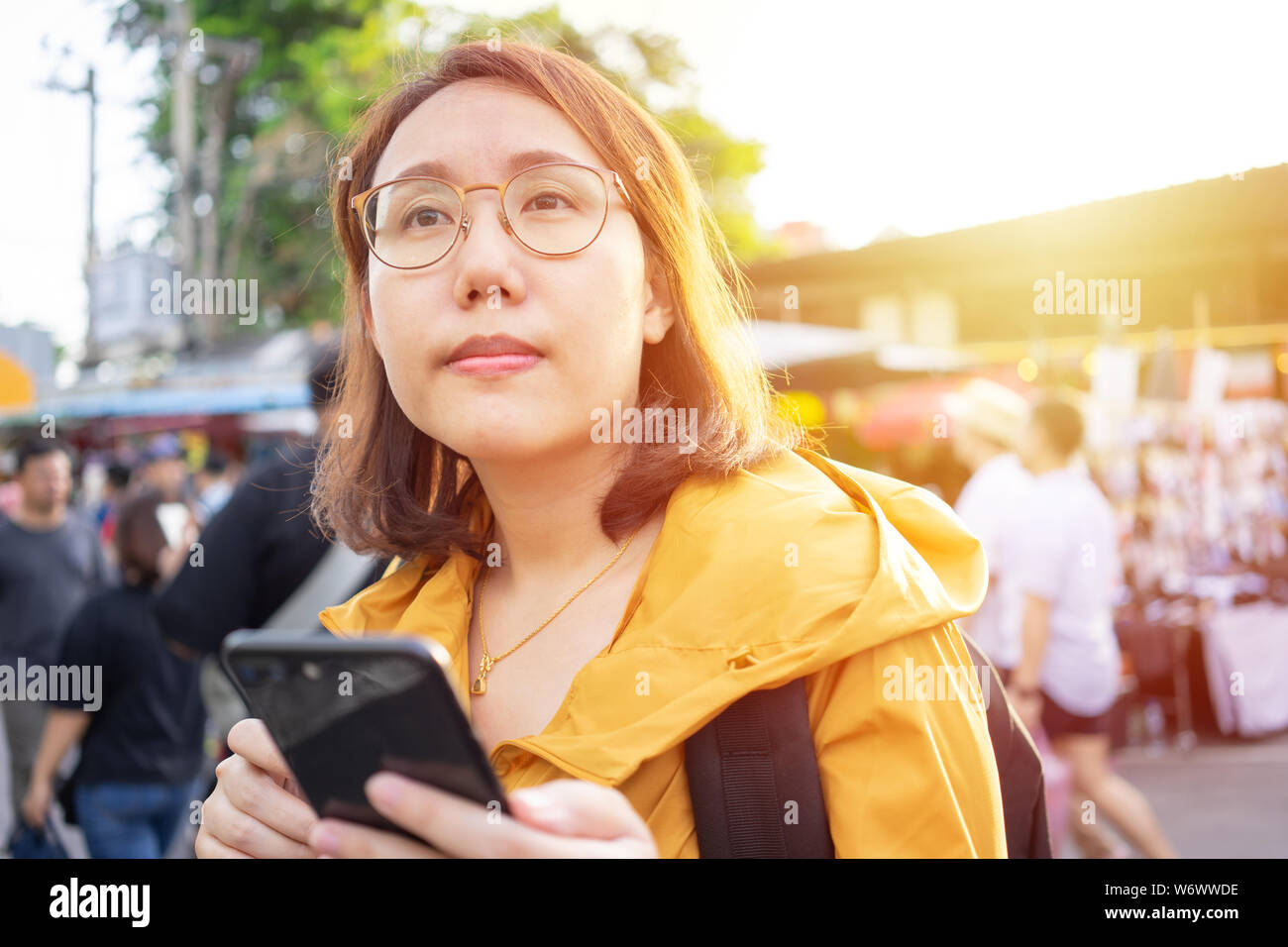 Portrait belles femmes asiatiques stand à tenir dans le marché de Chatuchak smartphones en Thaïlande. Bangkok est une attraction touristique pour les étrangers. Banque D'Images