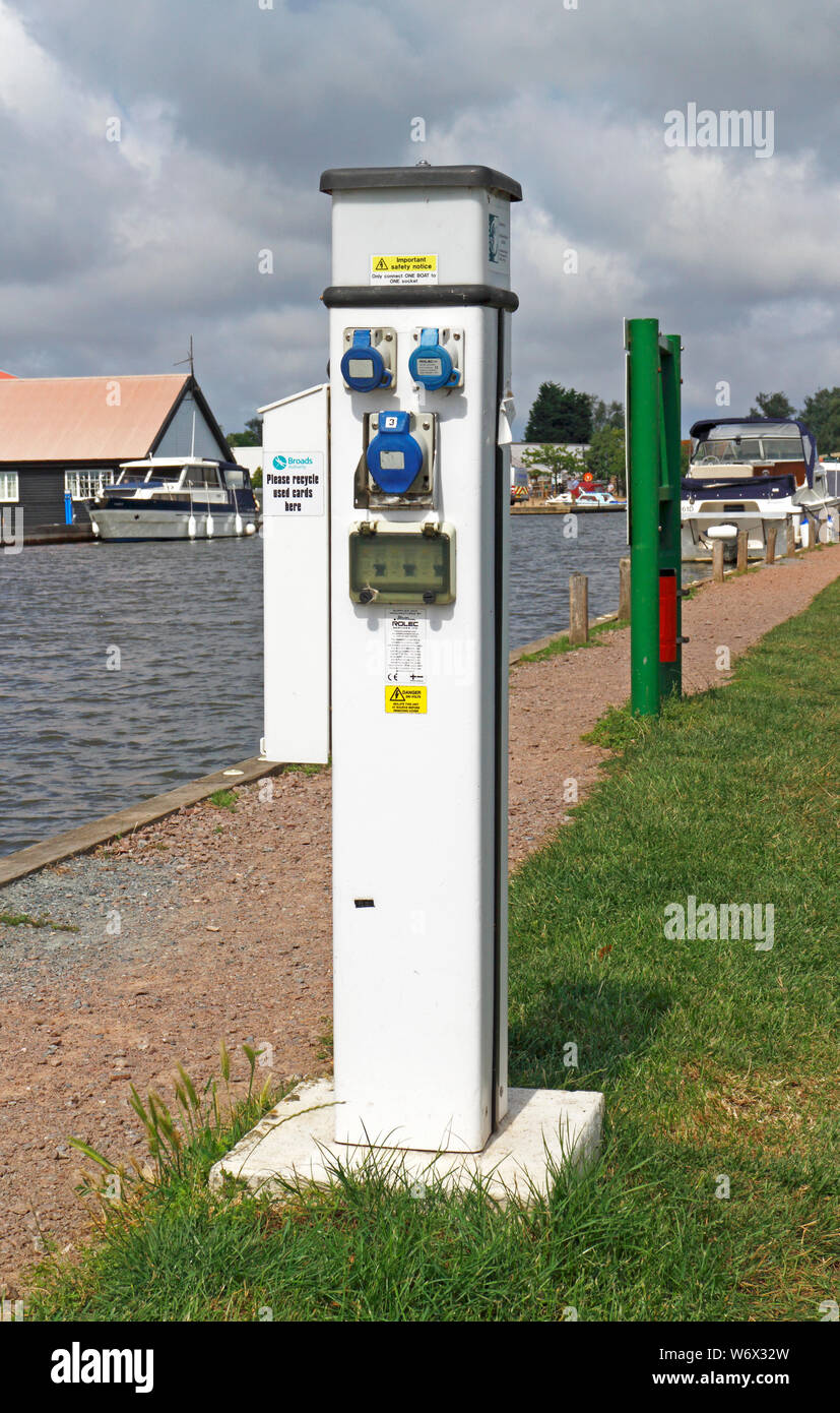 Un bateau au point de recharge batterie moorings sur la rivière Thurne sur les Norfolk Broads à Repps avec Bastwick, Norfolk, Angleterre, Royaume-Uni, Europe. Banque D'Images