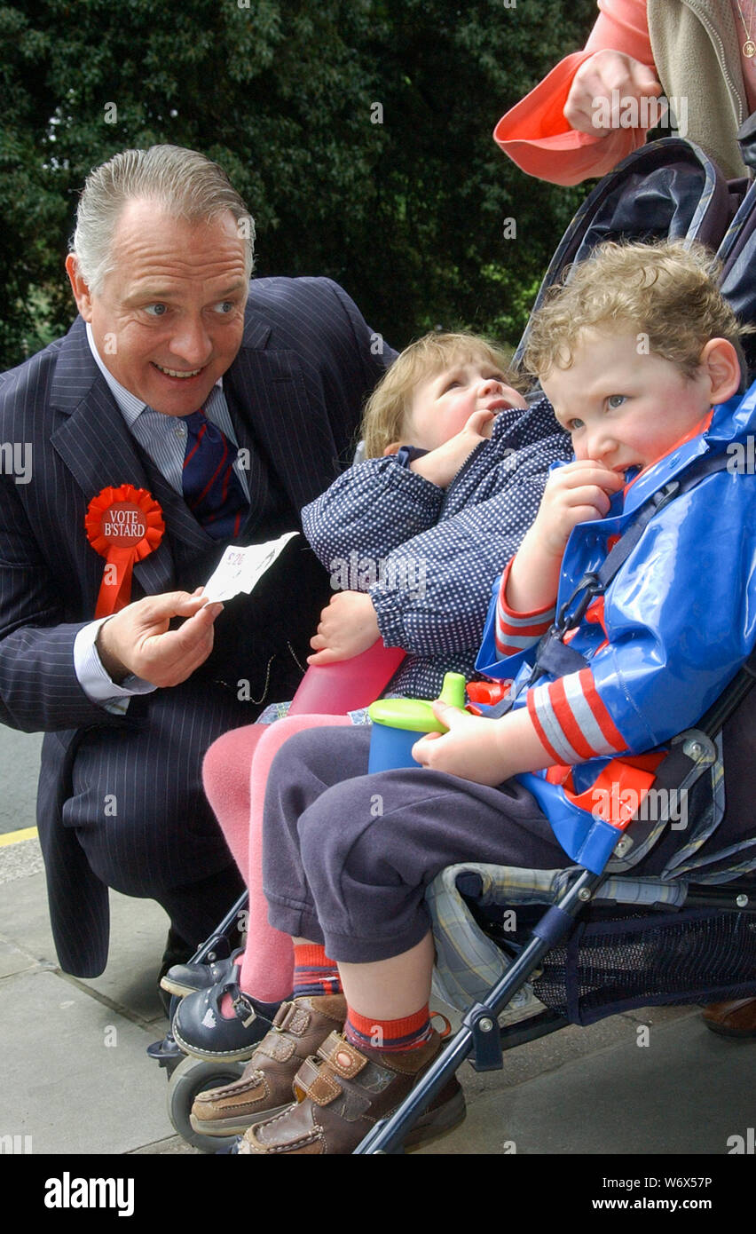 Acteur Rik Mayall sur walkabout de caractère comme MP Alan B'Stard, la promotion de la production de théâtre de tournée de "The New Statesman" dont il a été en vedette dans au Malvern Theatres. Church Street, Great Malvern, Worcestershire. Alan B'Stard MP offrir aux enfants de l'argent. Le 15/05/2007 Banque D'Images