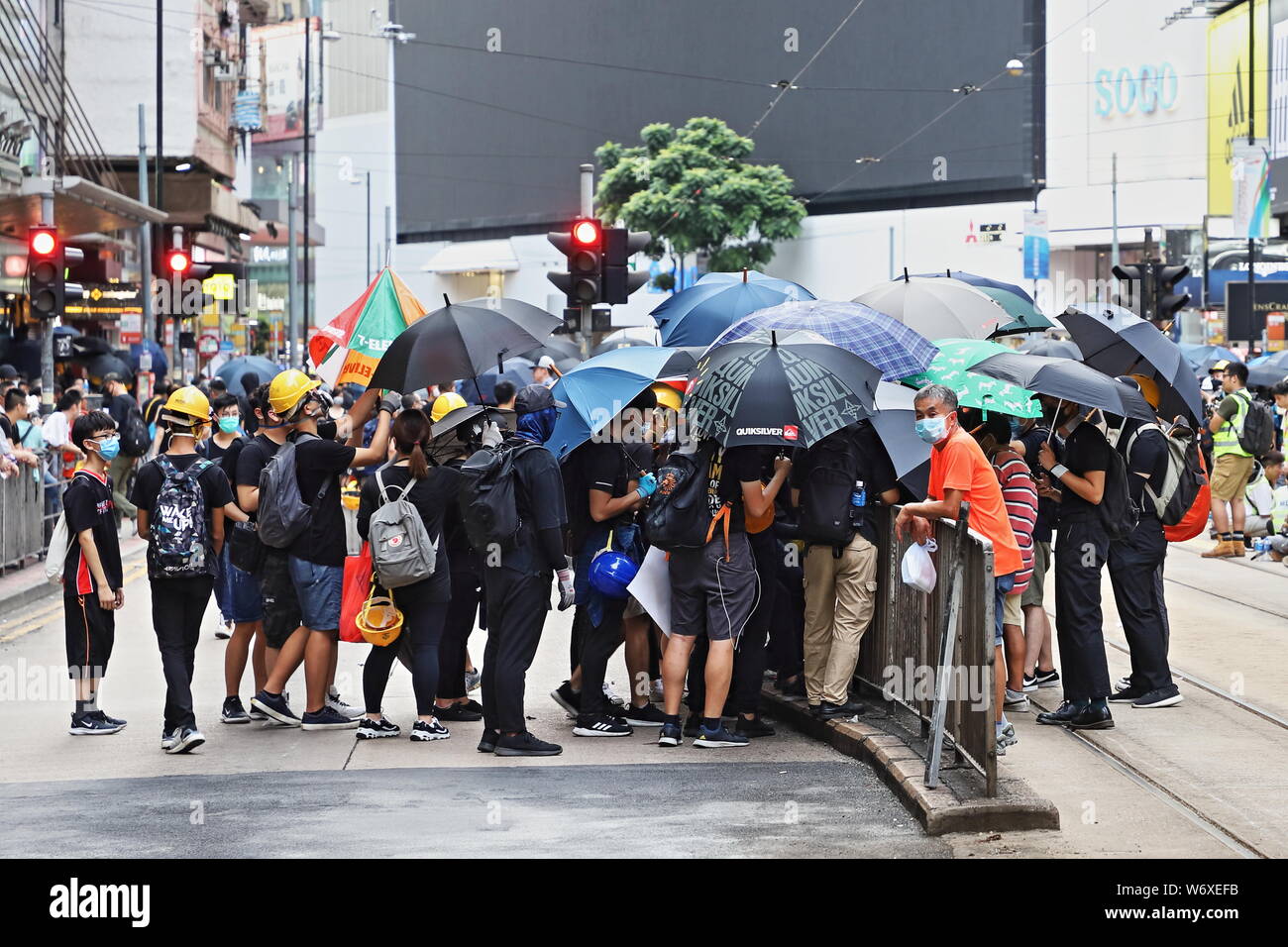 CAUSEWAY BAY, HONG KONG - Juillet 25, 2019 Chine : dissimuler leur identité avec parasols, tandis qu'ils dévisser et enlever les barrières pour piétons à l'avance Banque D'Images