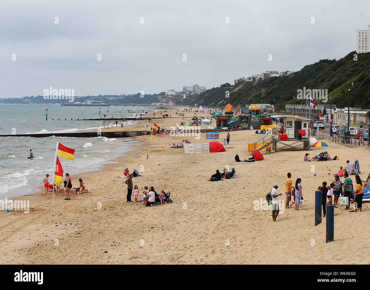 Les gens sur la plage sur une journée d'été couvert à Bournemouth. Les orages pourraient apporter plus de misère à des parties de la UK déjà touchées par les inondations avec l'émission d'avertissements météorologiques par le Met Office pour une bonne partie du nord de l'Angleterre et des Midlands. Banque D'Images