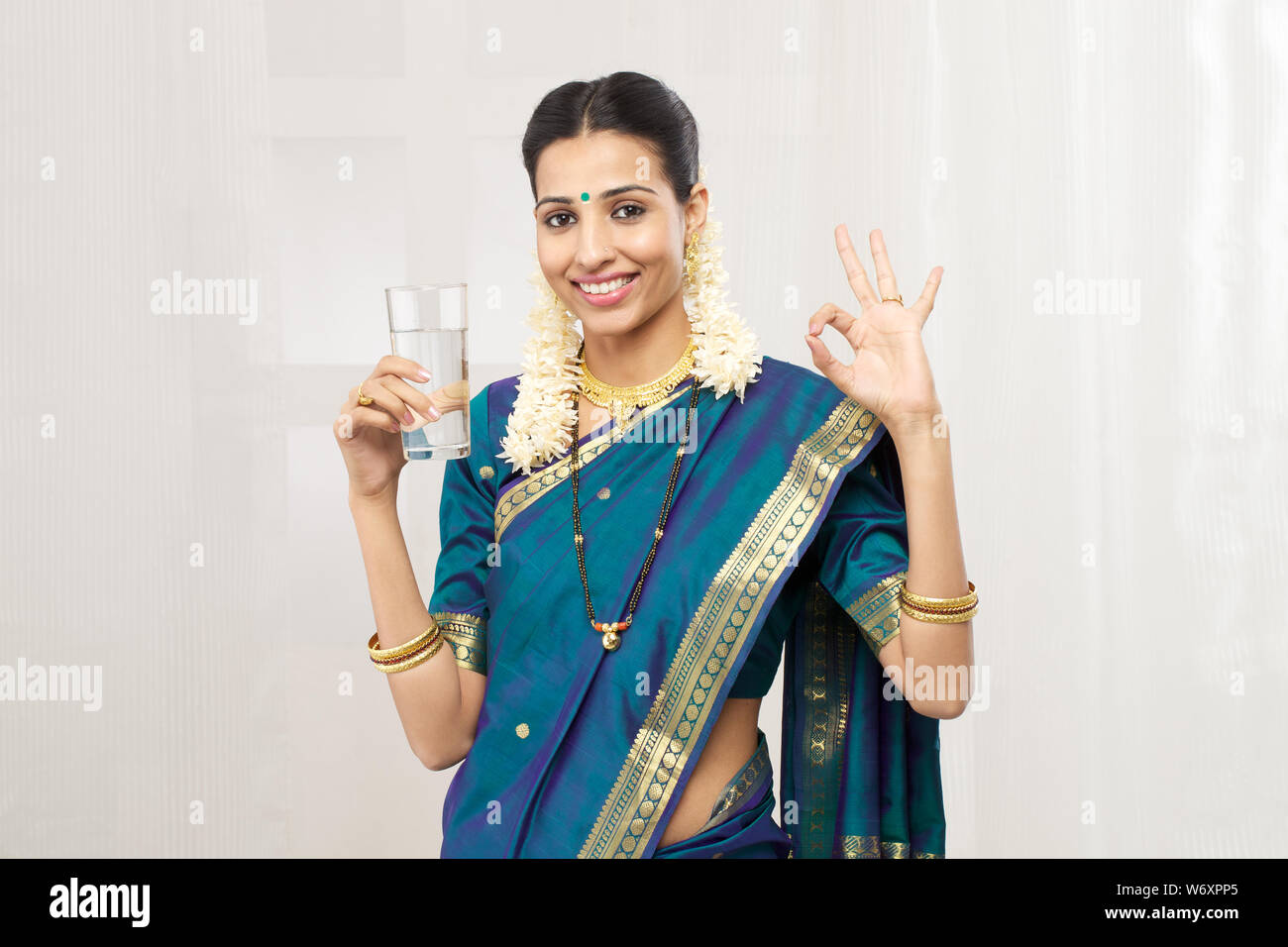 Femme indienne du Sud tenant un verre d'eau et souriant Banque D'Images