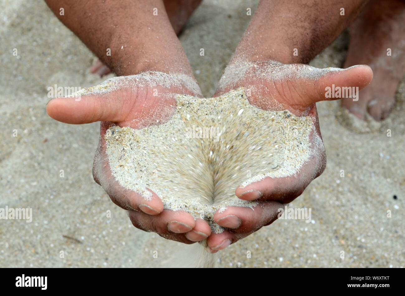 ADN humain : un homme et une femme qui squatter sur la plage de Tybee ont du sable qui coule à travers leurs mains. Banque D'Images