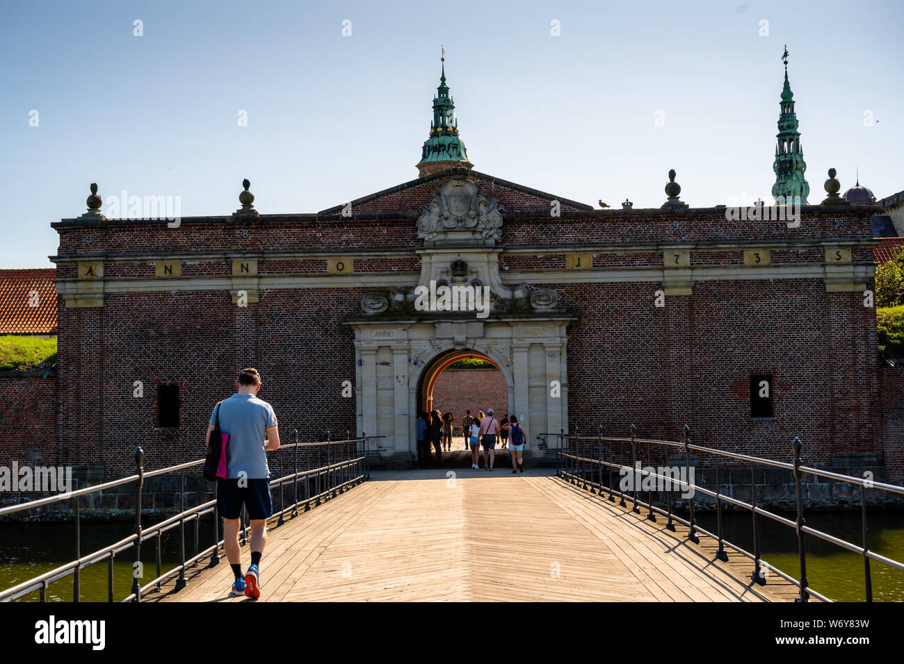 Kronborg, Danemark -- le 26 juillet 2019. Un touriste passant sur un pont-levis au-dessus d'un fossé sur son chemin vers le Château de Kronborg. Banque D'Images