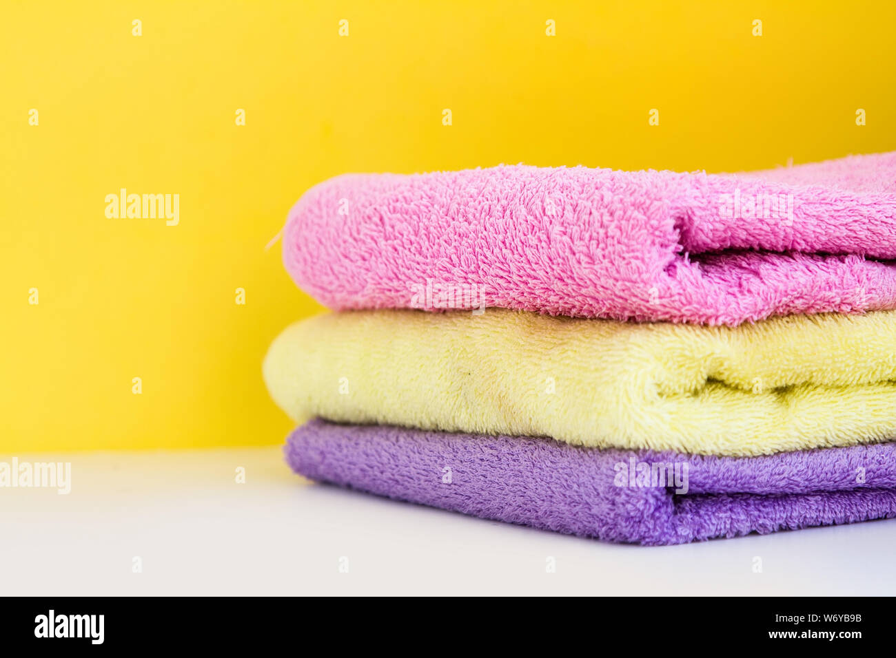 Trois serviettes de ratine multicolores ont un mur jaune sur fond blanc. Copy Space Banque D'Images