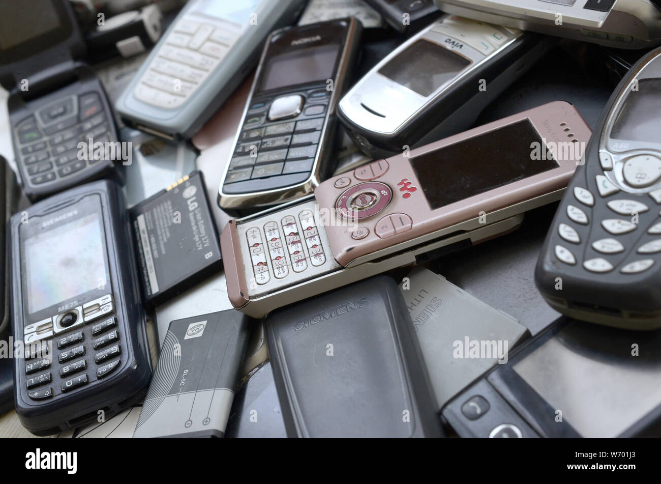 KHARKIV, UKRAINE - le 30 juillet 2019 : Groupe de vieux téléphones mobiles obsolètes utilisées et les batteries. Le recyclage de l'électronique se trouve dans de nombreuses marques gros tas fermer Banque D'Images