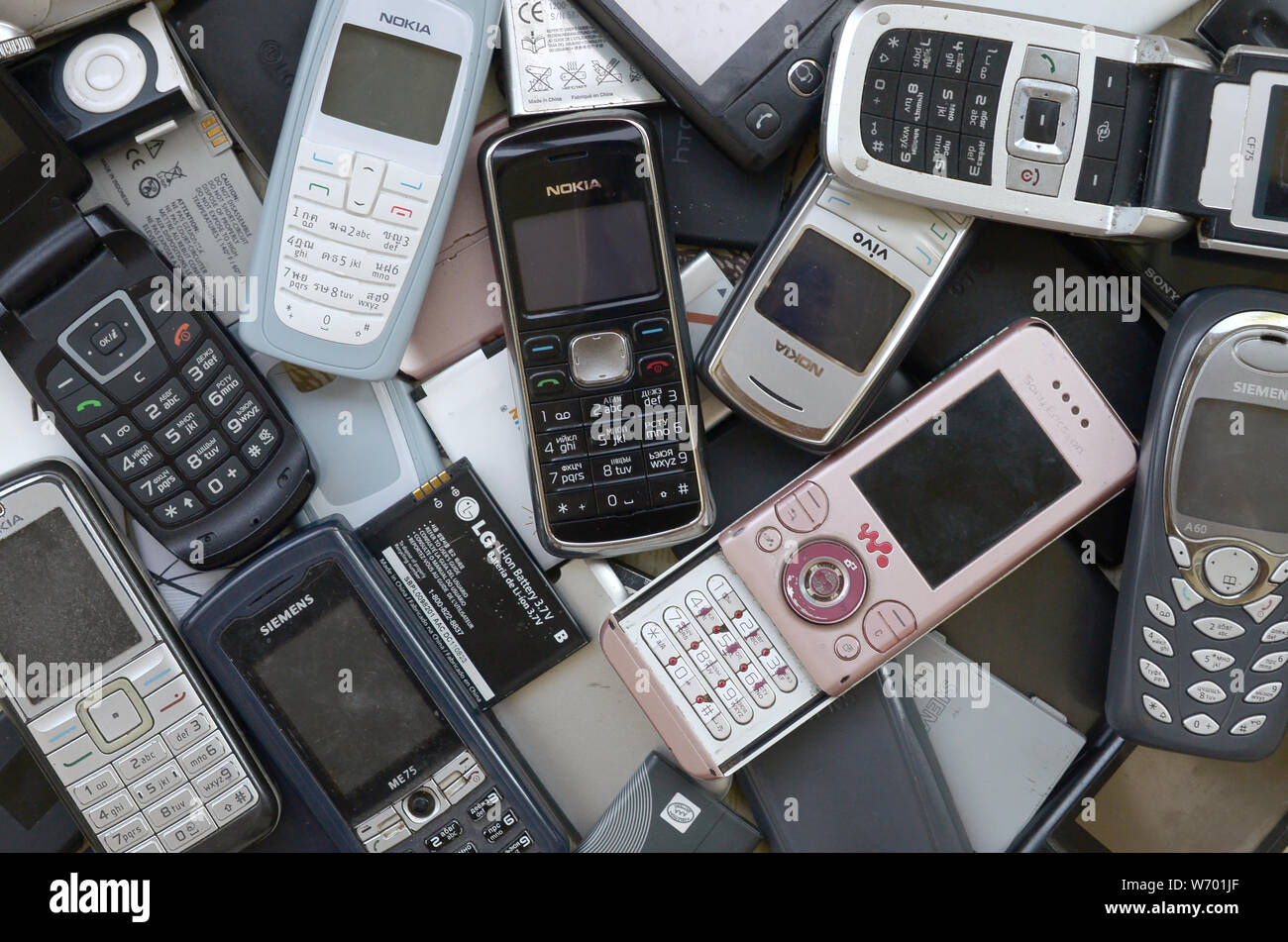 KHARKIV, UKRAINE - le 30 juillet 2019 : Groupe de vieux téléphones mobiles obsolètes utilisées et les batteries. Le recyclage de l'électronique se trouve dans de nombreuses marques gros tas fermer Banque D'Images