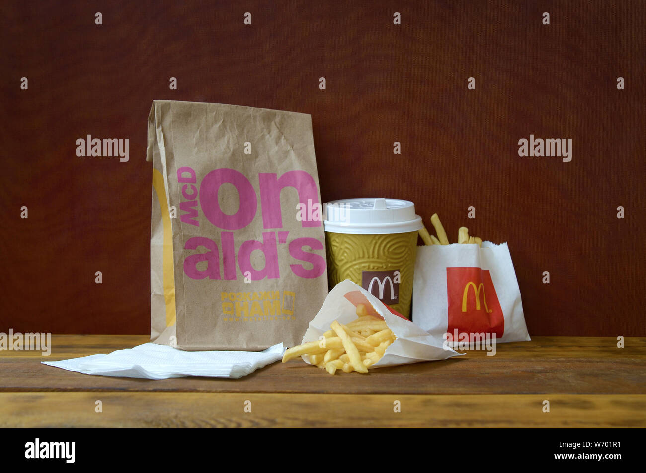 KHARKIV, UKRAINE - 1 août 2019 : McDonald's à emporter sac de papier et la malbouffe sur table en bois. McDonald's Corporation est la plus grosse chaîne o Banque D'Images