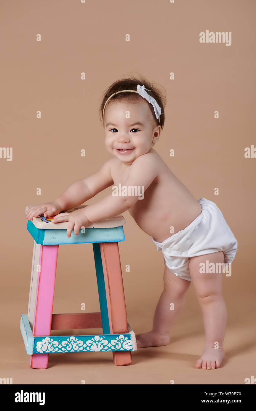 Happy pretty baby girl attente chaire en arrière-plan studio Banque D'Images