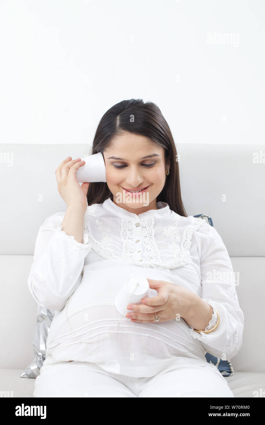 Une femme enceinte peut porter un téléphone à l'oreille Banque D'Images
