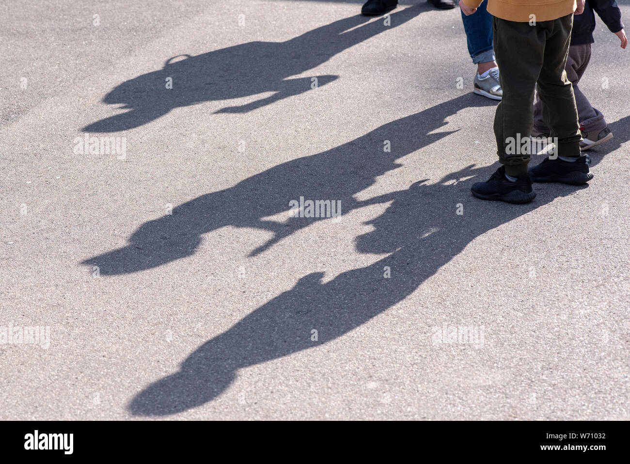 Ombres et silhouettes de trois enfants jouant dans une rue sur la surface de la route d'asphalte comme arrière-plan ou de texture Banque D'Images