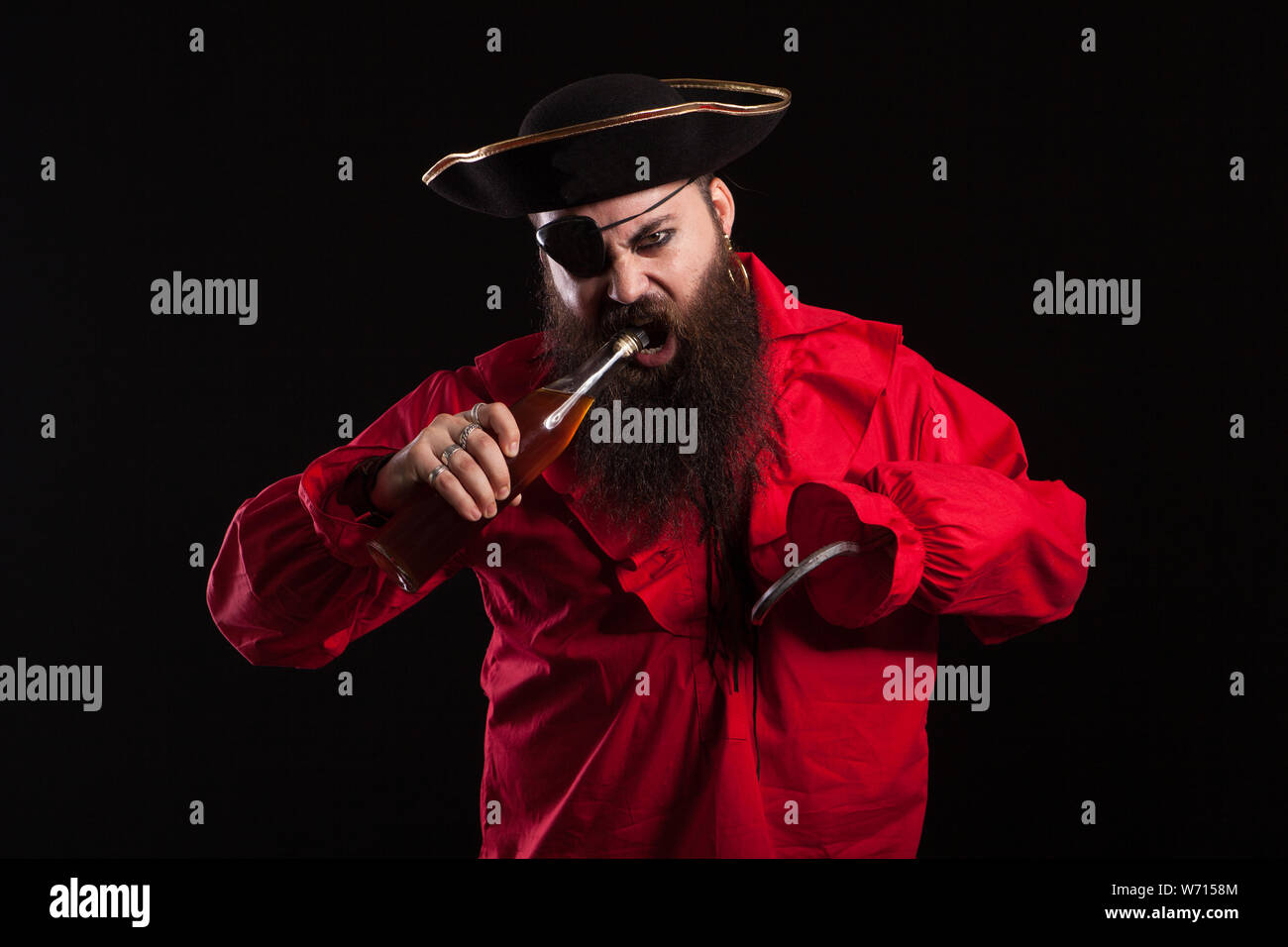 Portrait d'homme barbu habillé comme un pirate pour Halloween. Pirate à l'ouverture de la bouteille avec sa bouche. Banque D'Images