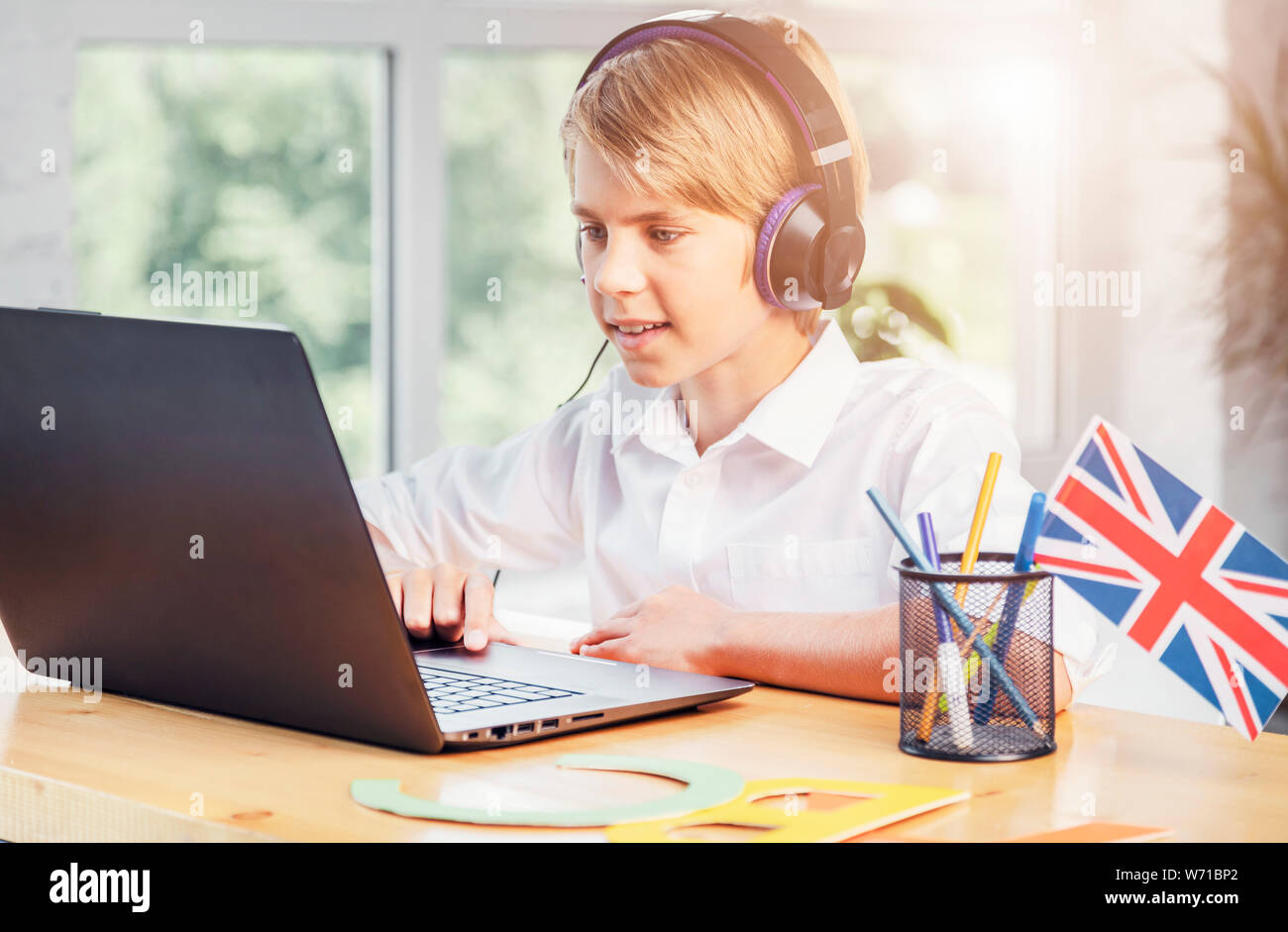 Les jeunes anglais en ligne stydying écolier using laptop Banque D'Images