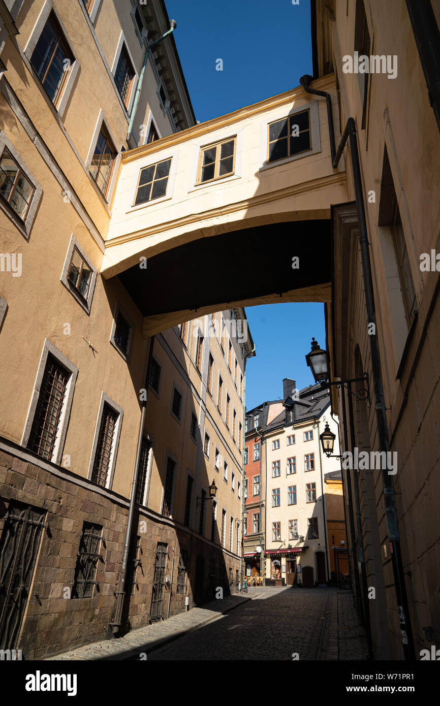 Pont / Arch entre les anciens bâtiments de couleur ocre à Gamla Stan (vieille ville), Stockholm, Suède Banque D'Images