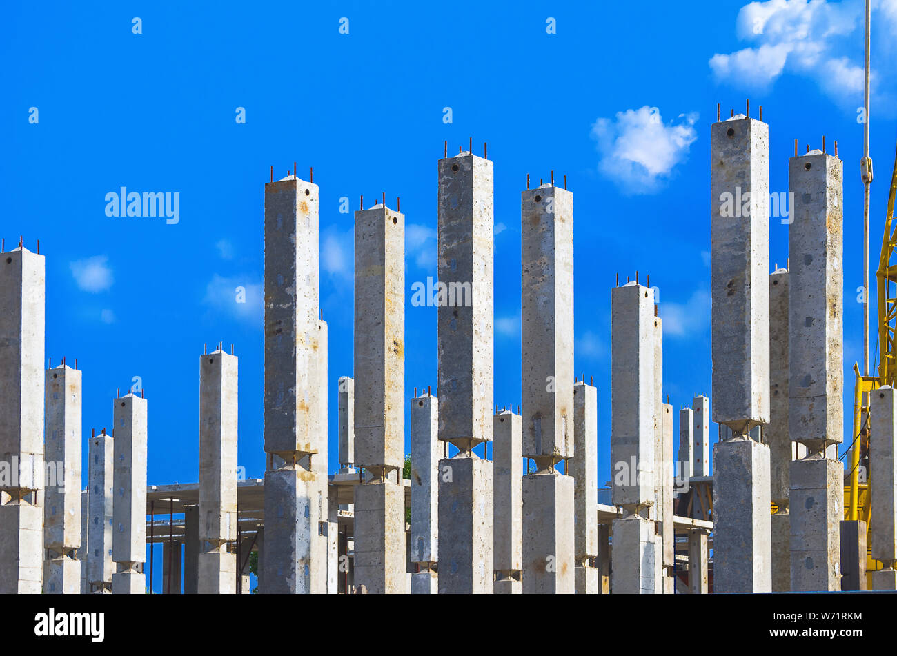 Des colonnes de béton armé verticale avec les armatures at Construction Site, ciel bleu et nuages blancs en arrière-plan. L'immobilier, les immeubles d'habitation Urb Banque D'Images