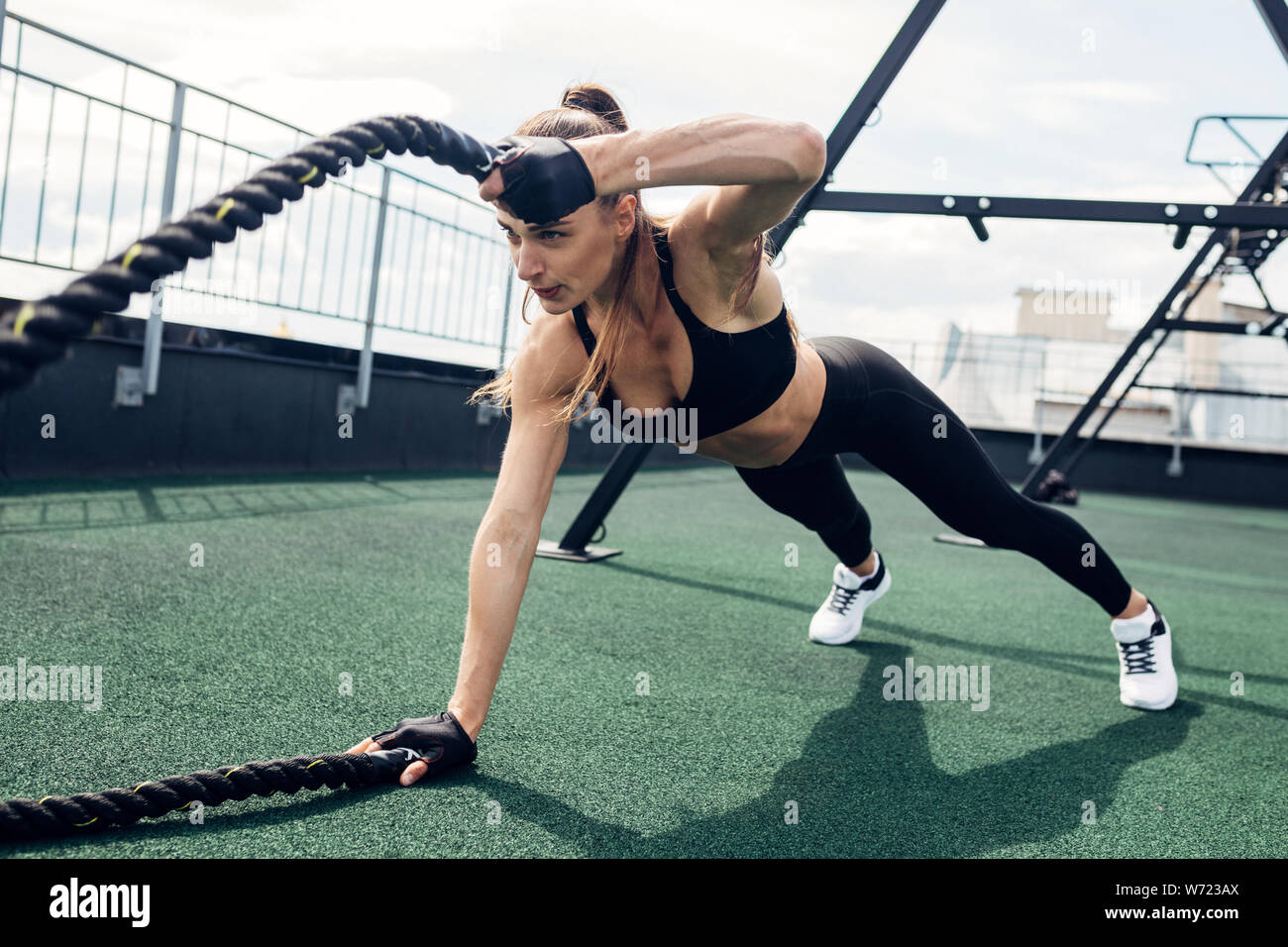 Femme de remise en forme avec l'exercice en plein air. corde bataille Athlète hors travail musculaire sur une terrasse. Banque D'Images