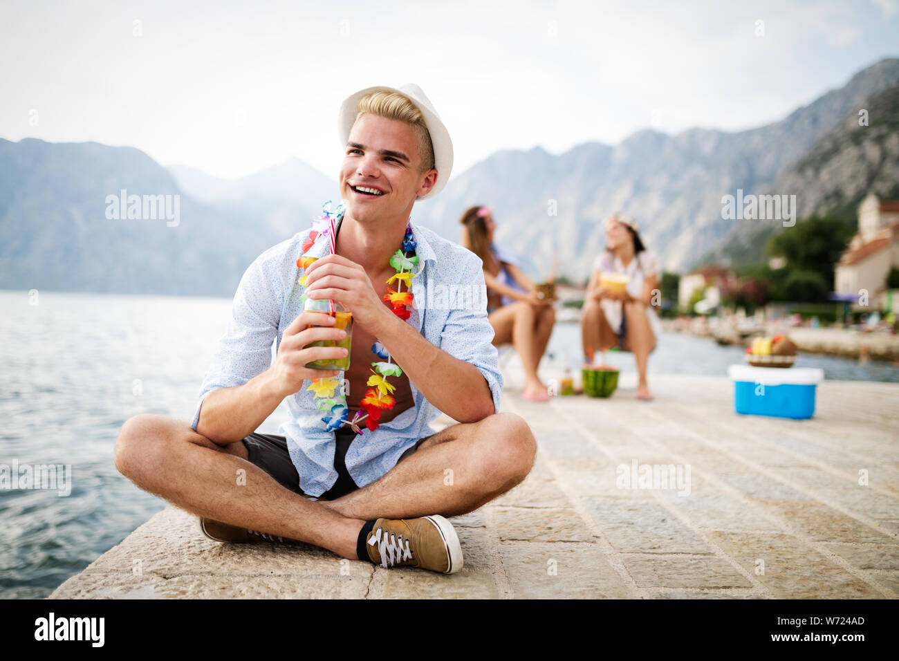 Les jeunes gens heureux avec boissons détente sur la plage Banque D'Images