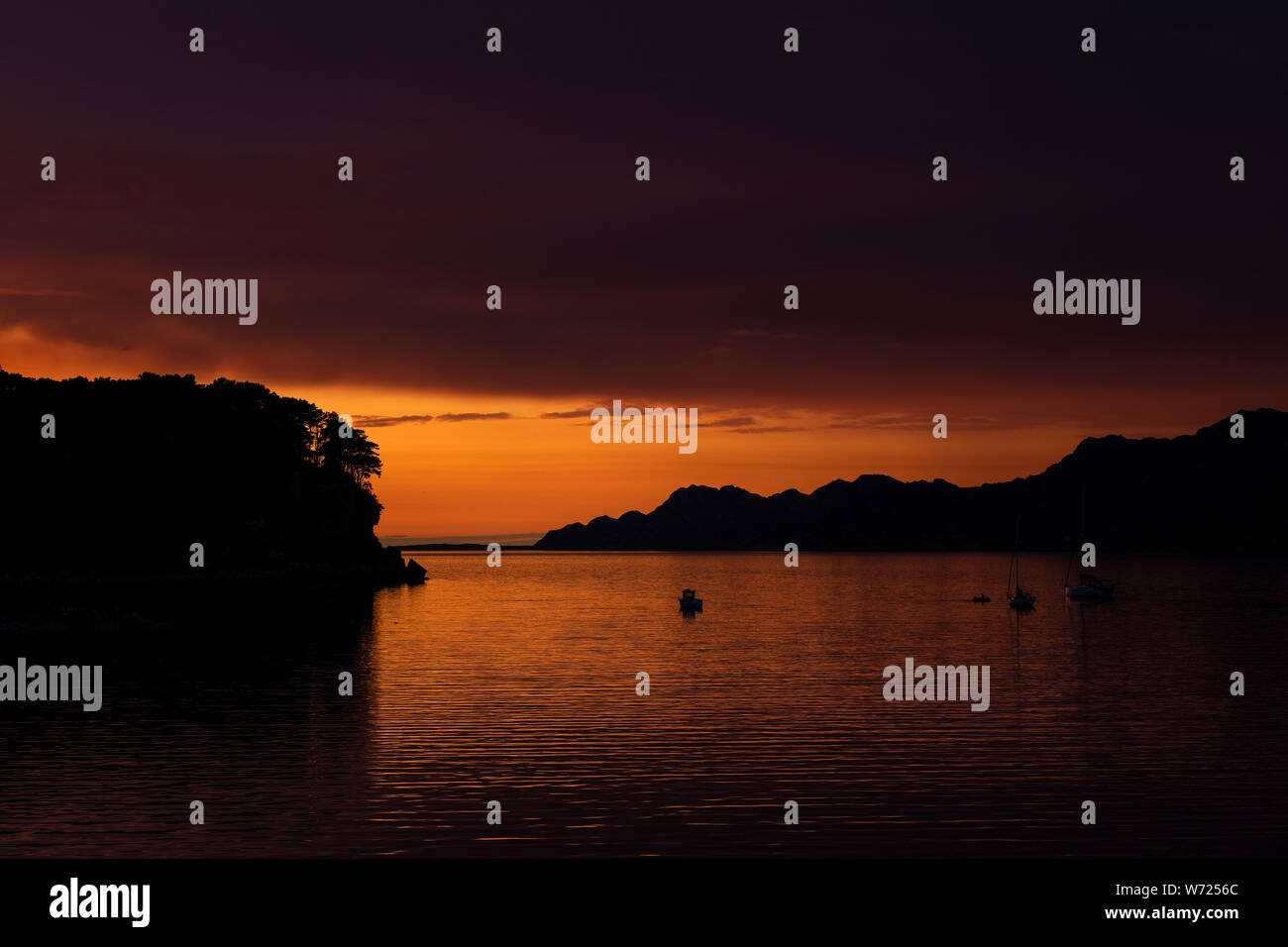 Coucher du soleil au large Sheildaig sur la côte ouest de l'Ecosse avec un seul bateau de pêche et yachts amarrés dans les eaux calmes près de la côte. Banque D'Images