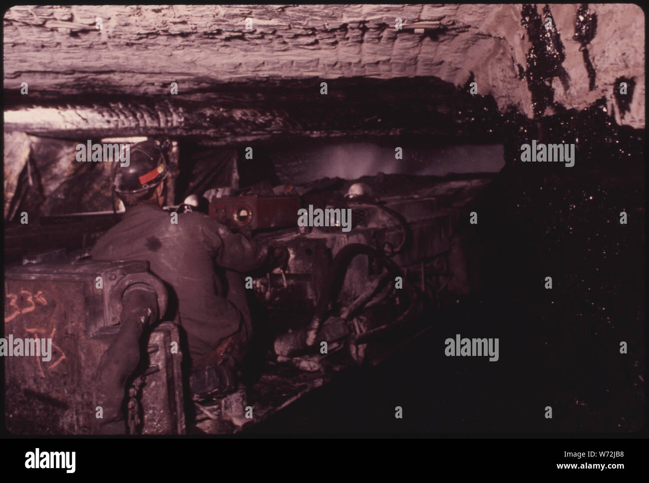 L'HOMME L'EXPLOITATION D'UN MINEUR CONTINU À VIRGINIA-POCAHONTAS COAL MINE # 3 PRÈS DE RICHLANDS, Virginie. Remarque LA PULVÉRISATION D'EAU À L'AVANT DE LA MACHINE POUR GARDER LA POUSSIÈRE DE CHARBON PARTICULES DE L'AIR. La chaux ou de la poussière de roche EST ÉGALEMENT UTILISÉ POUR CONTRÔLER LES PARTICULES EN SUSPENSION DANS L'PROBLÈME. Le mineur continu PASSE LE CHARBON À UNE NAVETTE VOITURE QUI SORT DU TUNNEL POUR LE TRANSPORT À L'AIDE DE TAPIS DE LA MINE Banque D'Images