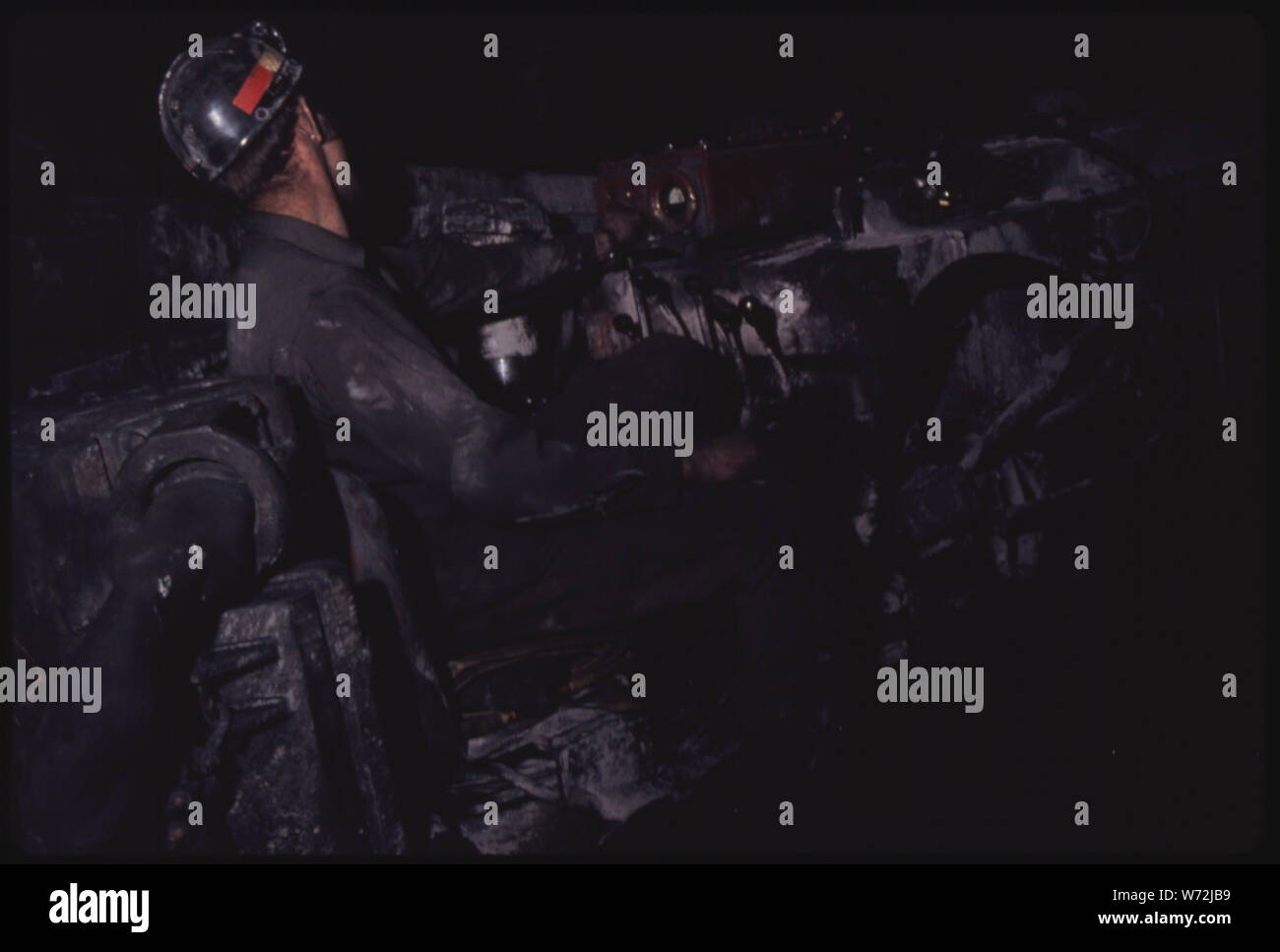 L'HOMME L'EXPLOITATION D'UN MINEUR CONTINU À VIRGINIA-POCAHONTAS COAL MINE # 3 PRÈS DE RICHLANDS, Virginie. Notez le FORT ROUGE EN FACE DE L'opérateur. Il COUPE AUTOMATIQUEMENT L'appareil si le gaz méthane ATTEINT UN CERTAIN NIVEAU. Le mineur continu PASSE LE CHARBON À UNE NAVETTE VOITURE QUI SORT DU TUNNEL À CONVOYEUR POUR LE TRANSPORT DE SORTIE DE LA MINE Banque D'Images