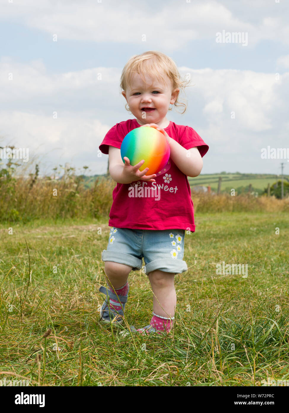 Enfant jouant avec une balle à l'extérieur en été, UK Banque D'Images