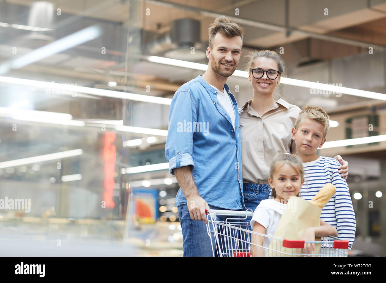 Portrait de jeune famille contemporaine posant dans un supermarché tout en profitant de l'épicerie, copy space Banque D'Images