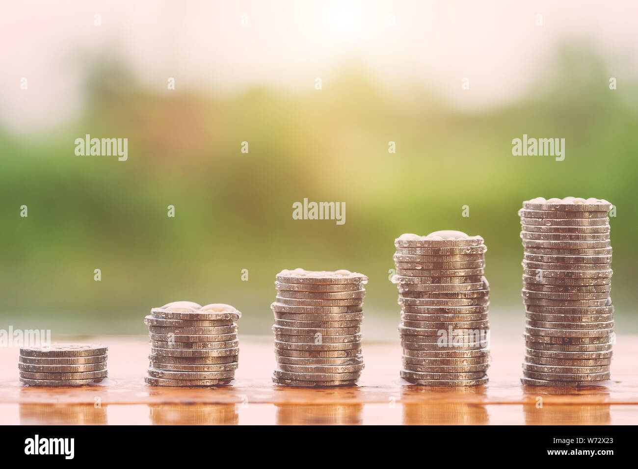 Différents niveaux de pile de pièces avec de l'eau tomber sur l'arrière-plan flou. La réussite de l'entreprise ou de l'argent concept croissante Banque D'Images