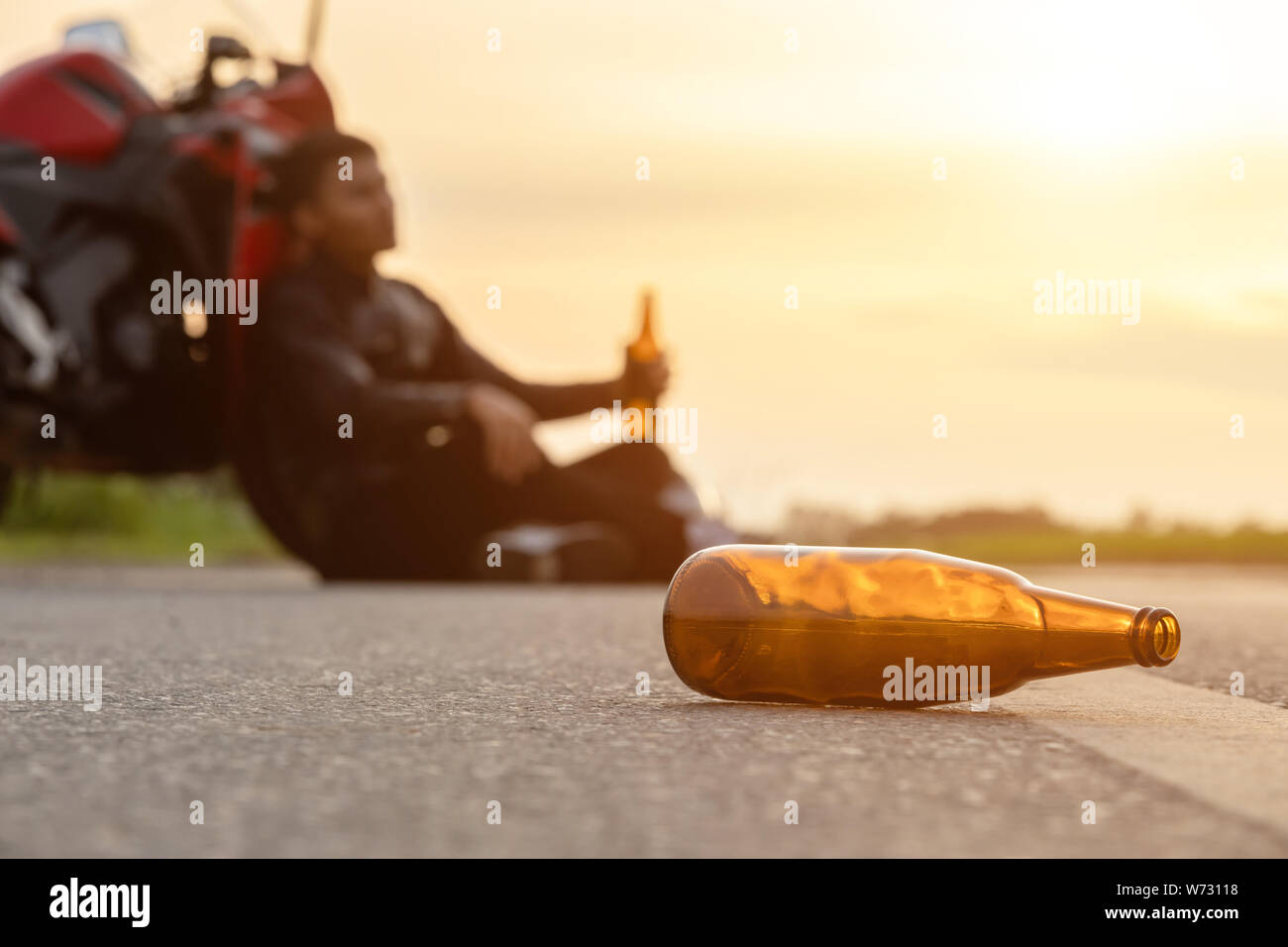 Motocycliste assis sur la route à côté de sa moto et de boire une bière ou  d'alcool. Safe ride concept Photo Stock - Alamy