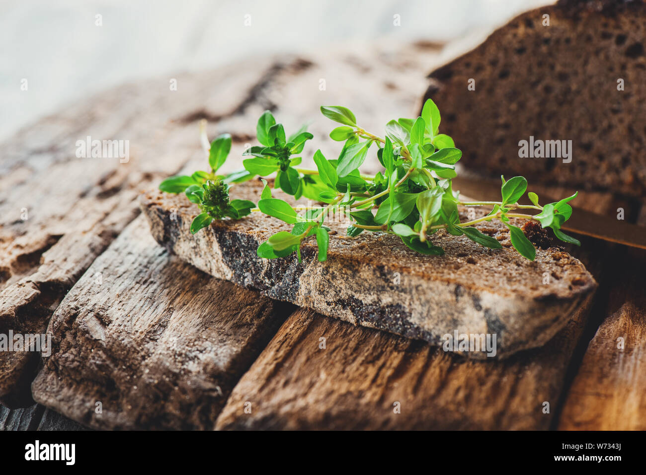 Un morceau de pain de seigle avec un bouquet de thym sur un ancien support en bois. Farmer's Petit-déjeuner tôt. Banque D'Images