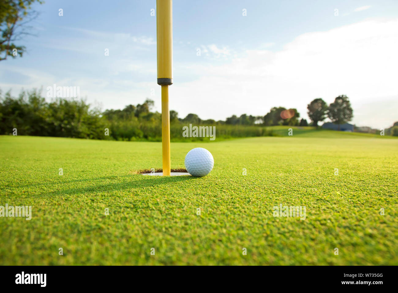 Close up low angle view d'une balle de golf sur le green près du trou sur un après-midi ensoleillé Banque D'Images